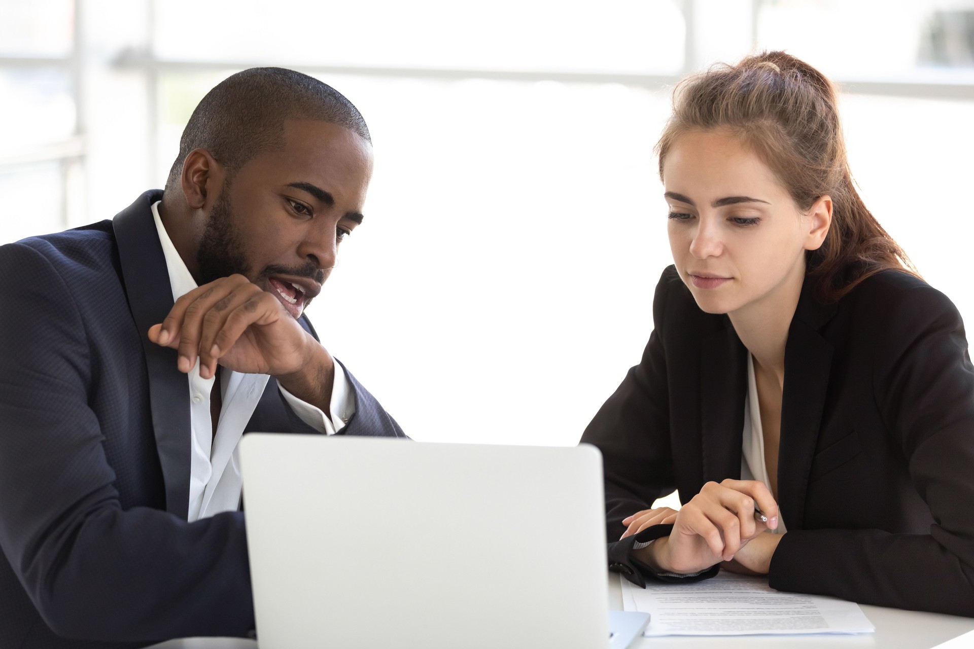 Multiracial millennial team working together in office using laptop