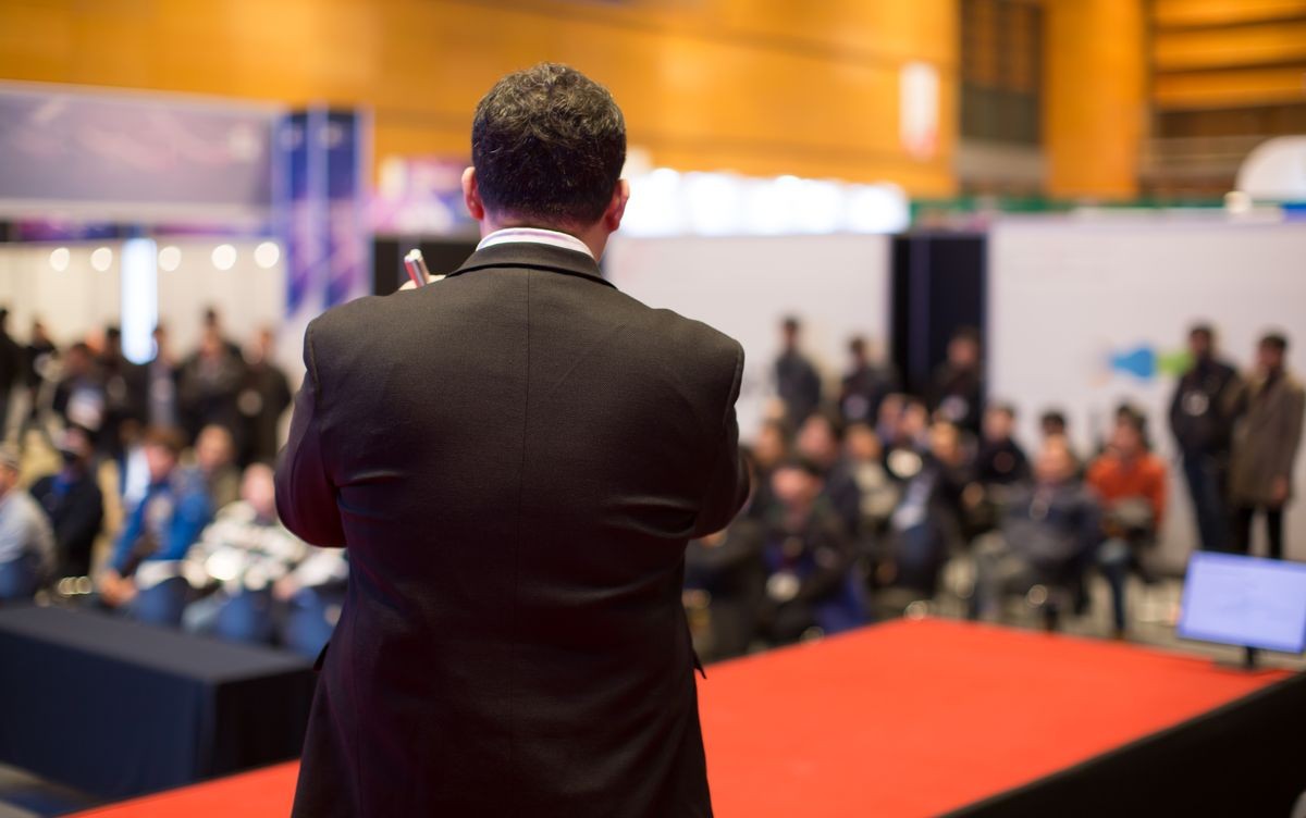 Presenter Presenting on Stage at Conference Meeting. Speaker at Professional Lecture. Unidentifiable Blurred De-focused. Tech Presenter and Audience. Corporate Executive Manager Presentation Seminar.
